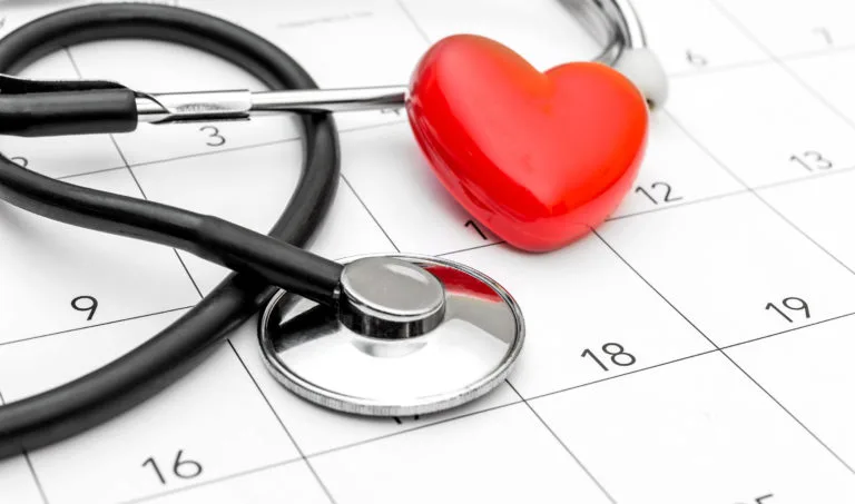 Red heart and stethoscope on white calendar