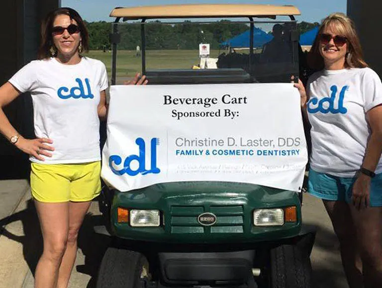 Two team members by a golf cart at community event