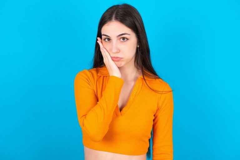 A woman holding her cheek with her hand